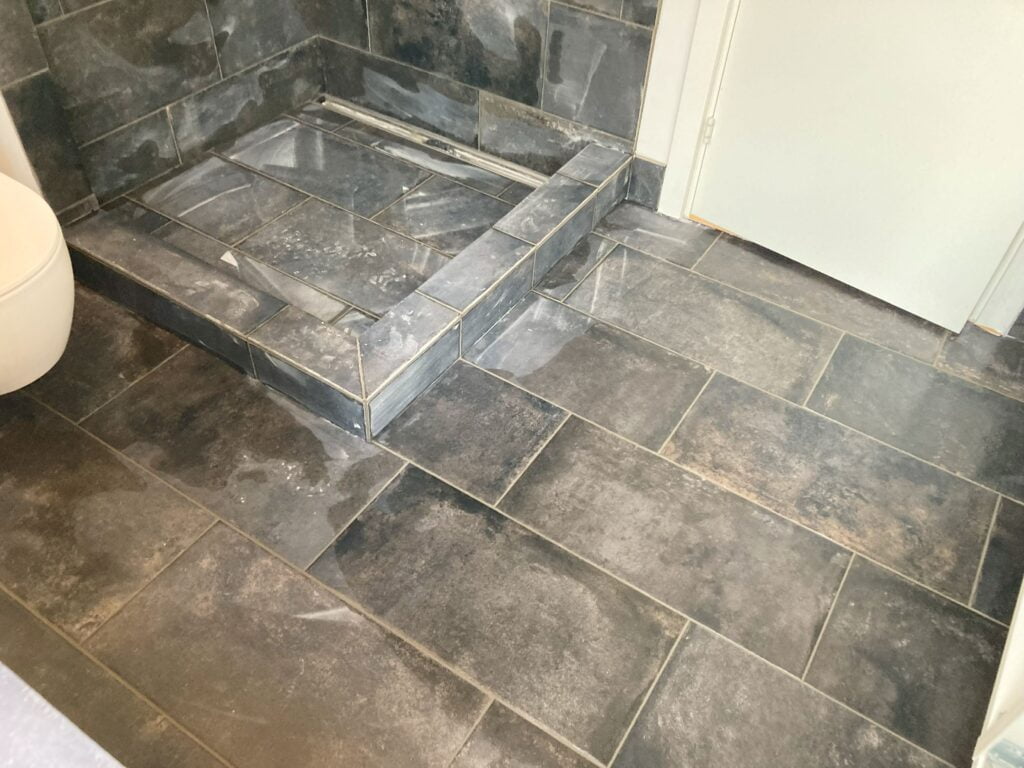 Gråt flisebelagt badeværelsesgulv med bruseniche