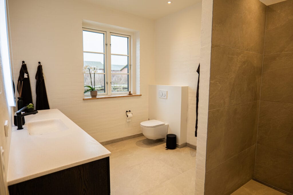 Moderne badeværelse med brusevæg og stort vindue.