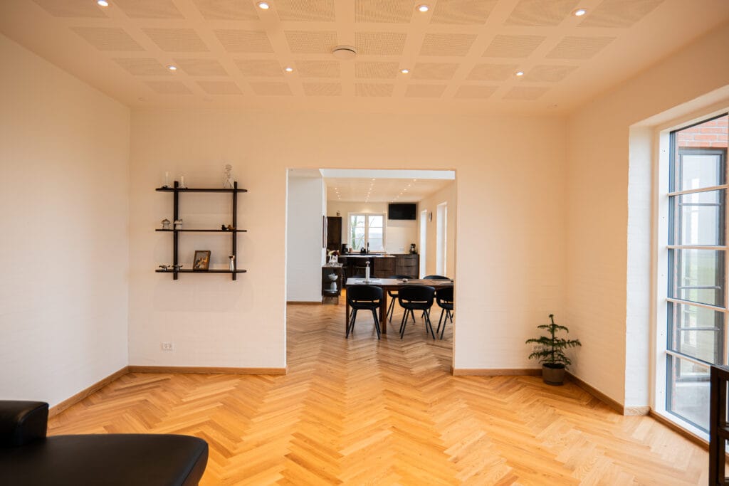 Moderne stue med træmønster gulv og spiseområde.